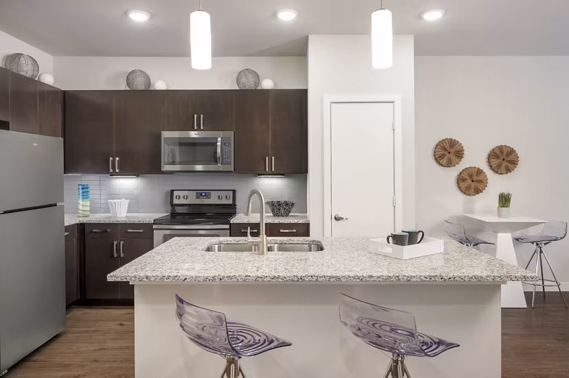 Sleek kitchen with modern appliances and granite countertops at The Upton at Longhorn Quarry Apartments