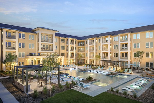 Outdoor pool with modern lounge chairs at The Upton at Longhorn Quarry Apartments