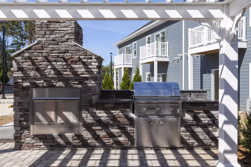 Outdoor grill area with modern seating at The Cornerstone Hauppauge Apartments, ideal for social gatherings in a luxury apartment community