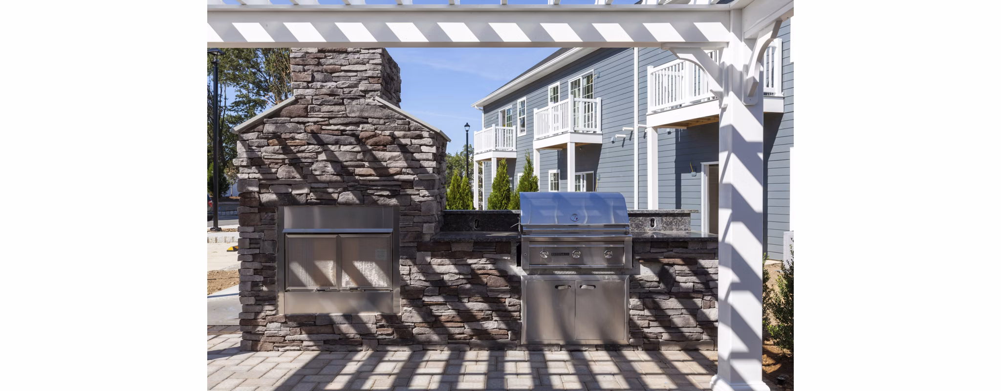 Outdoor grill area with modern seating at The Cornerstone Hauppauge Apartments, ideal for social gatherings in a luxury apartment community