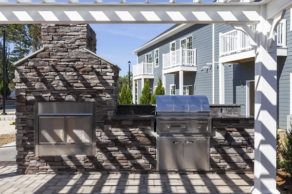 Outdoor grill area with modern seating at The Cornerstone Hauppauge Apartments, ideal for social gatherings in a luxury apartment community