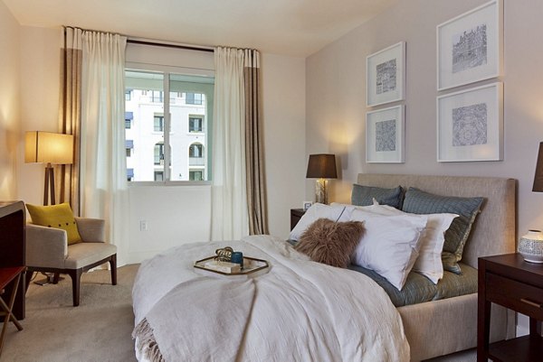 Spacious bedroom featuring a cozy bed, stylish lamps, and framed artwork in a luxury apartment
