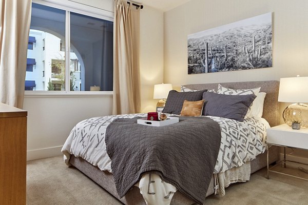 Cozy bedroom with elegant decor, plush bed, and natural light in luxury apartments