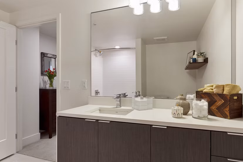 Modern bathroom featuring a large mirror, sleek sink, and decorative towels in luxury apartments