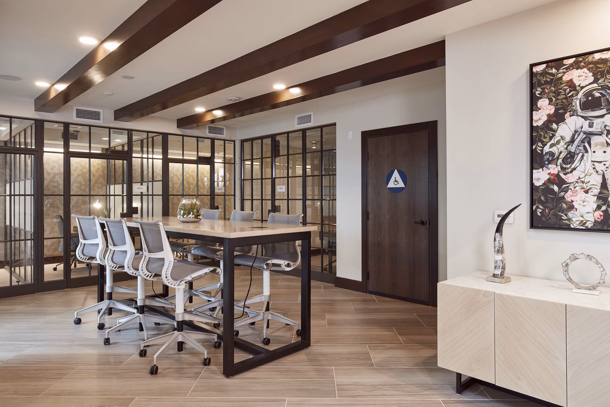 Modern conference room featuring a long table and glass walls with decorative artwork and plants
