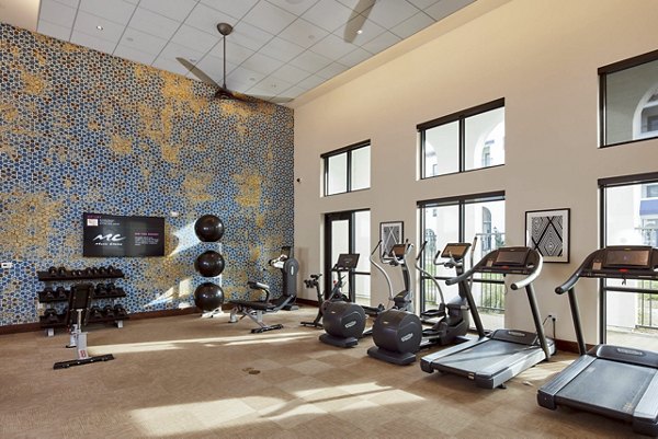 Modern fitness center with treadmills, exercise bikes, weight rack, and stability balls in luxury apartment community