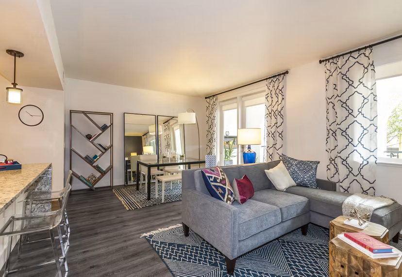 Spacious living room featuring modern decor and a large window in Encasa Apartments, a luxury property by Greystar