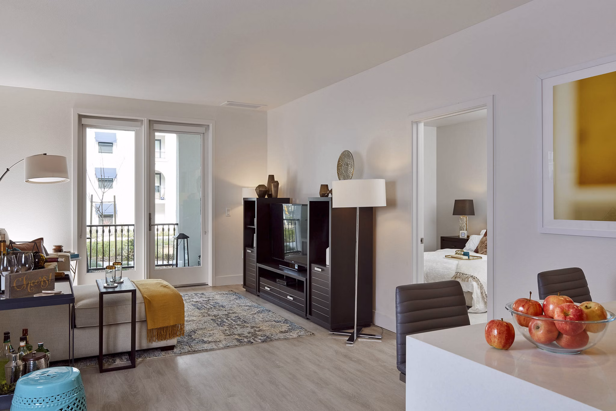 Modern living room and dining area with stylish furniture and a bowl of apples on the counter in luxury apartments