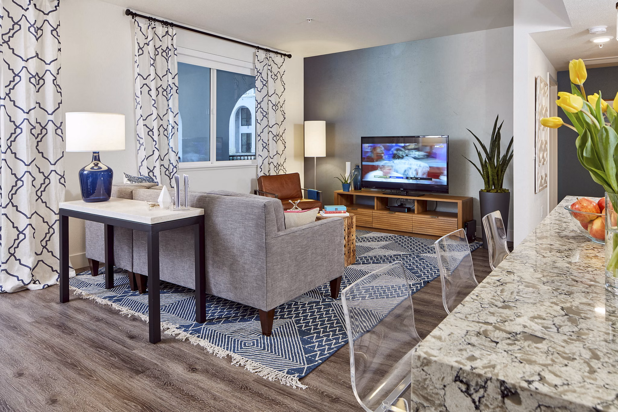 Spacious modern living room with a sofa, TV, and kitchen counter in luxury apartments
