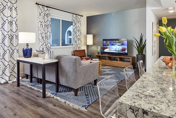 Spacious modern living room with a sofa, TV, and kitchen counter in luxury apartments