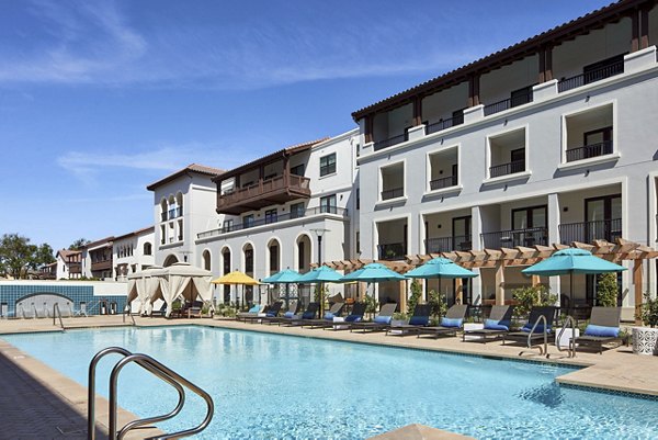 Luxurious swimming pool area with lounge chairs and umbrellas at luxury apartments