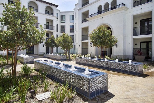 Luxury courtyard featuring decorative fountains and lush trees at a luxury apartment complex