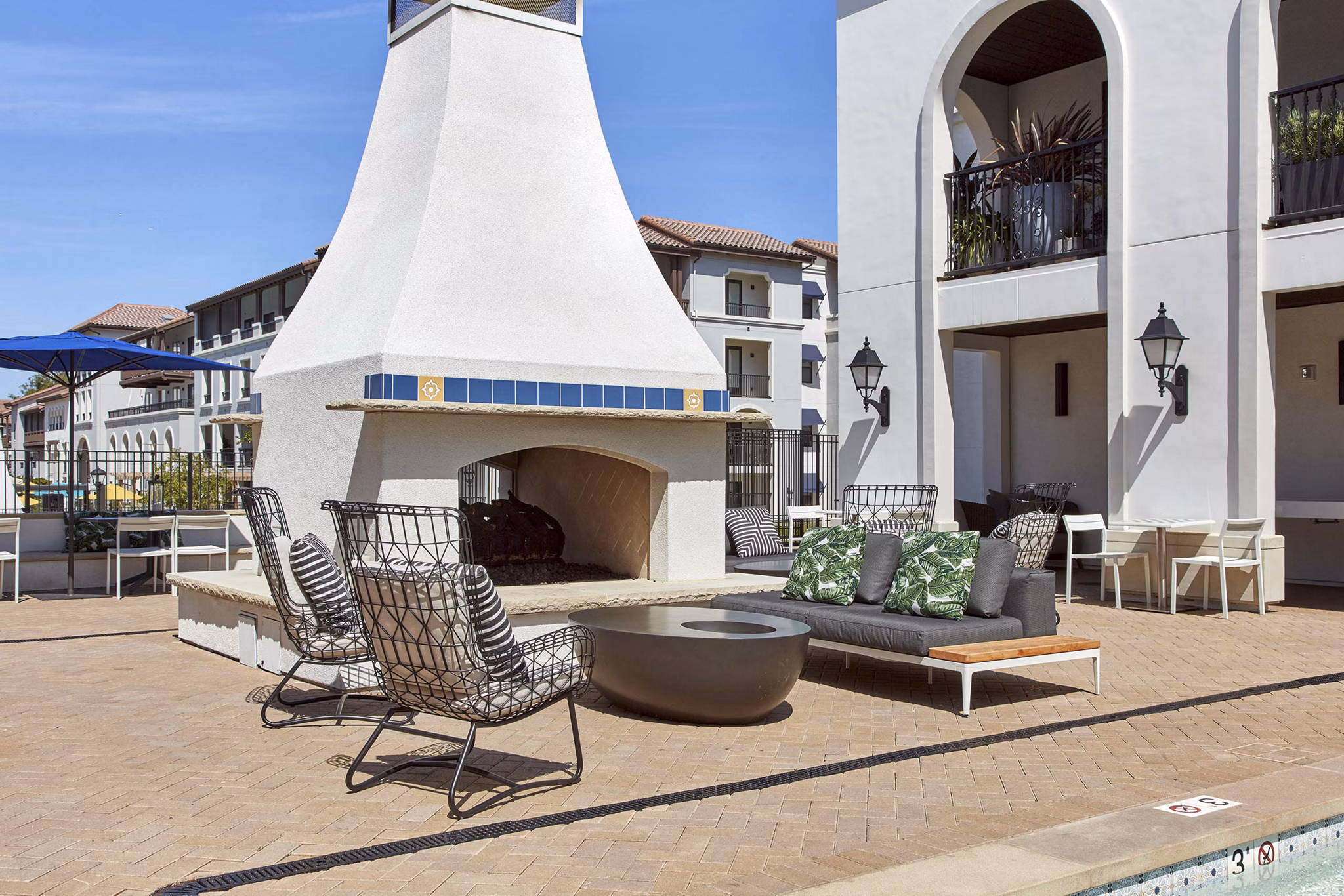 Cozy outdoor seating area with fireplace, chairs, and sofa at luxury apartments
