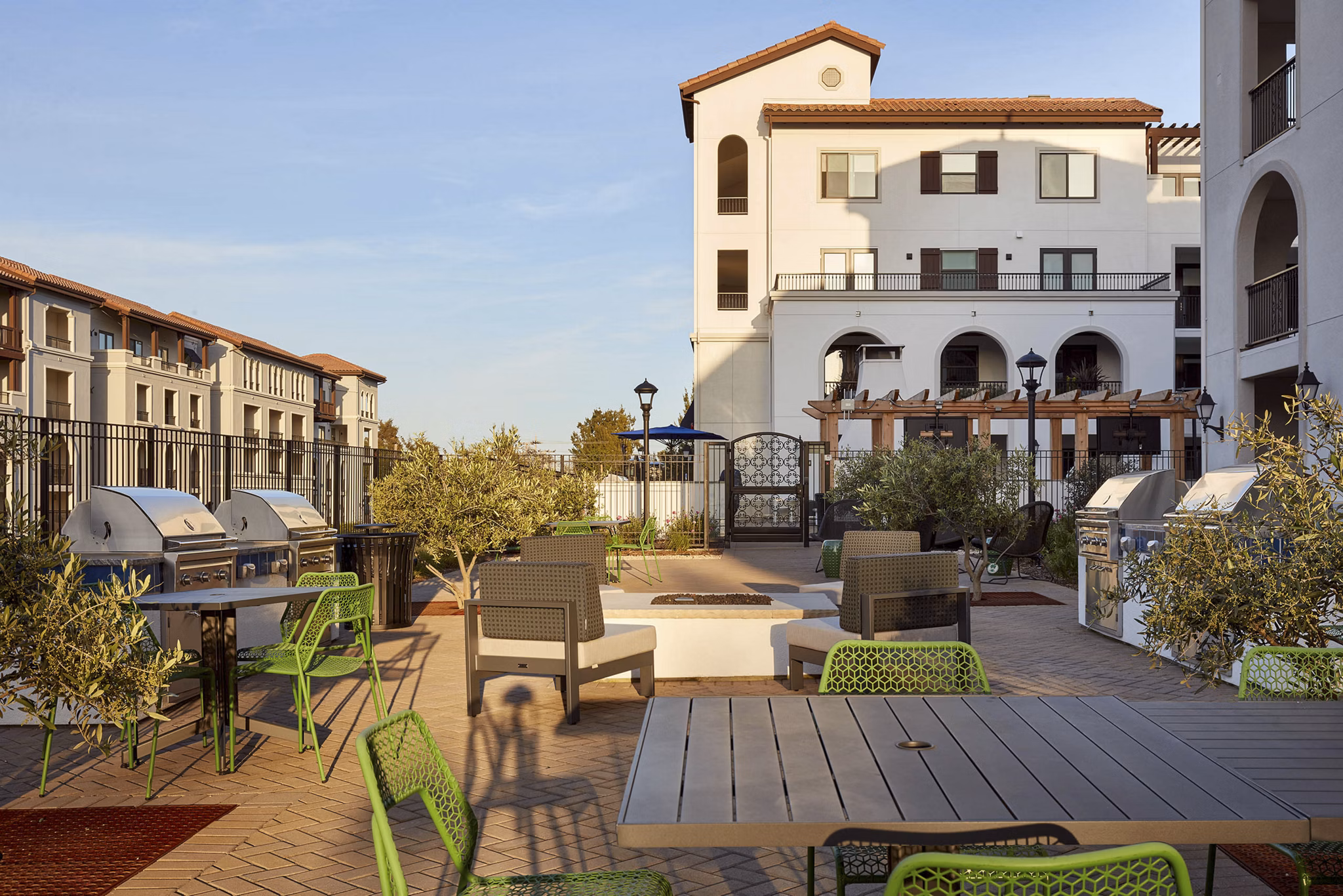 Outdoor patio area with tables, chairs, and grills at luxury apartments