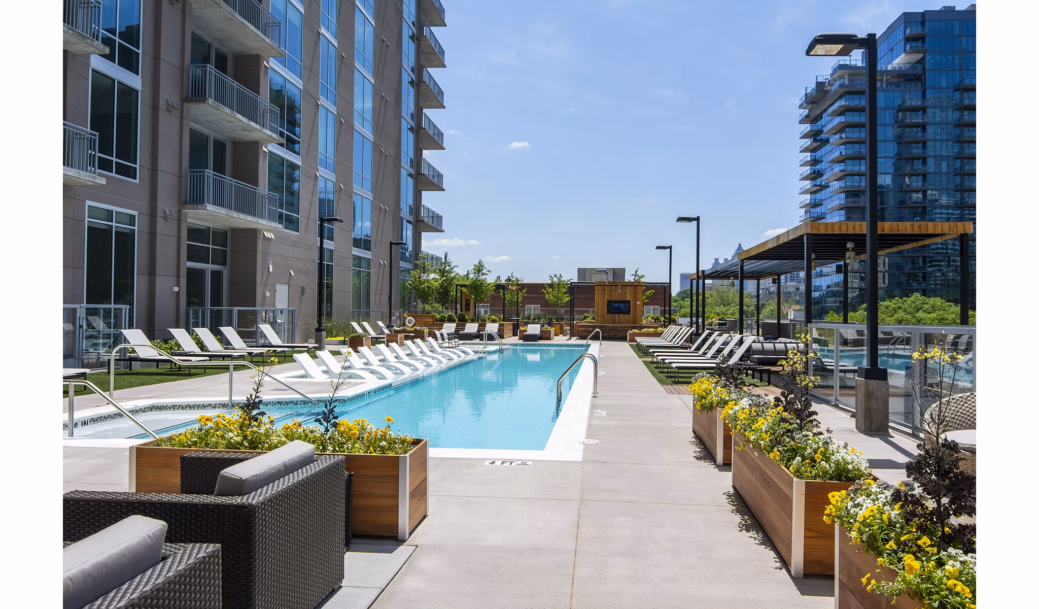 Inviting outdoor pool at Piedmont House Apartments with lounge seating and city skyline views, perfect for relaxation and social gatherings