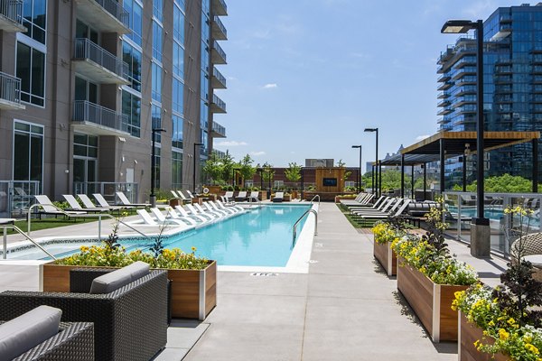 Inviting outdoor pool at Piedmont House Apartments with lounge seating and city skyline views, perfect for relaxation and social gatherings
