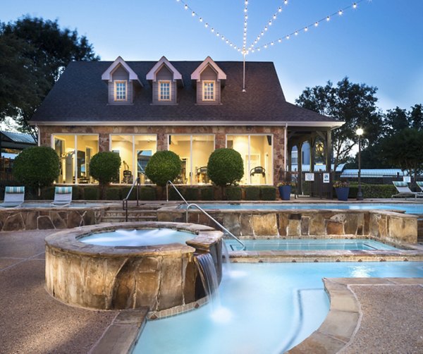 Sparkling pool surrounded by lounge chairs at Grapevine TwentyFour 99 Apartments
