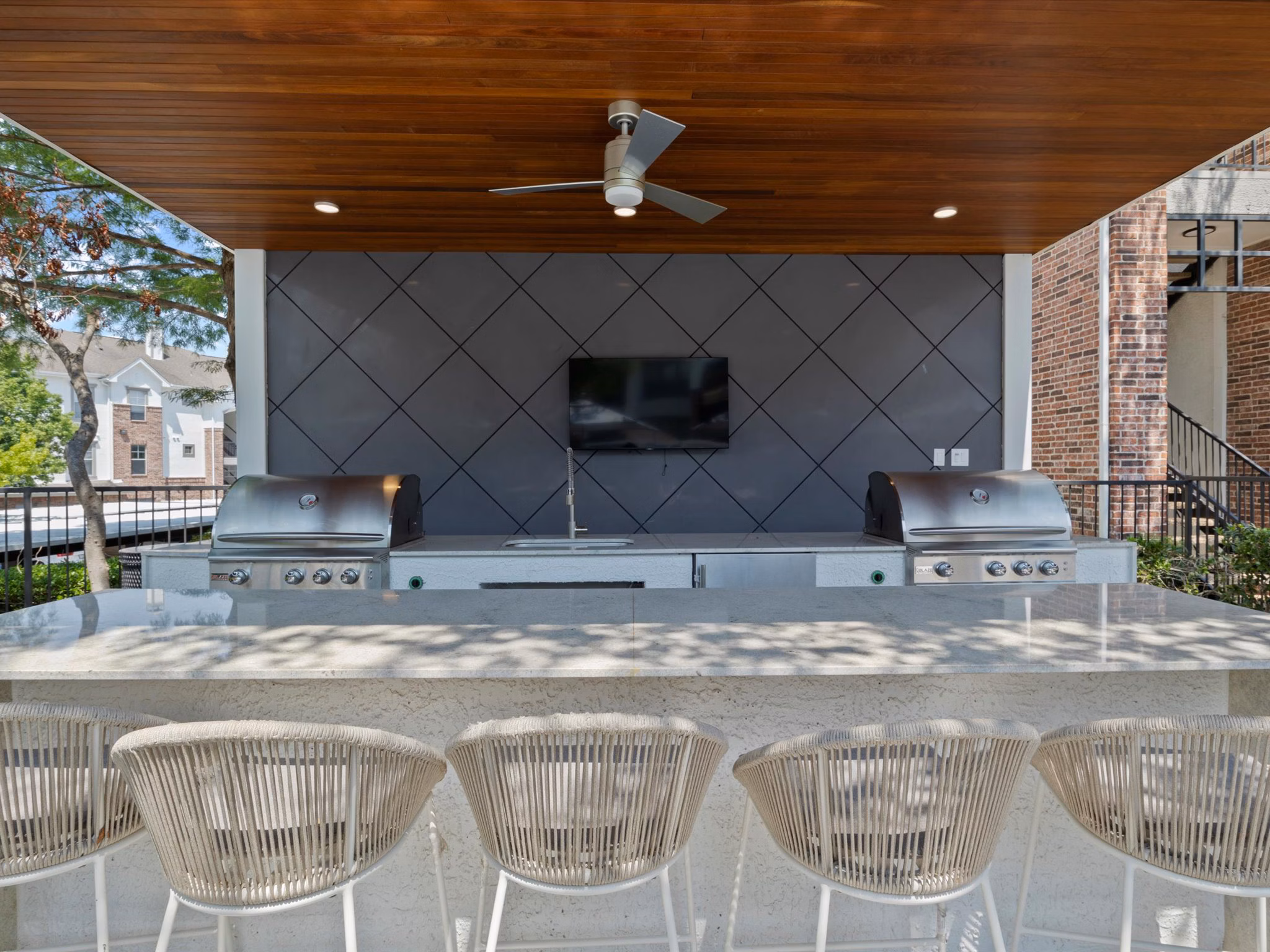 Outdoor grill area with modern seating at Eleven11 Lexington at Flower Mound Apartments, perfect for social gatherings and barbecues