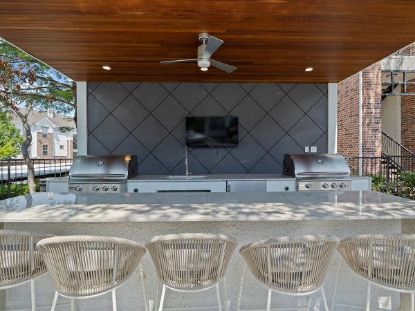 Outdoor grill area with modern seating at Eleven11 Lexington at Flower Mound Apartments, perfect for social gatherings and barbecues