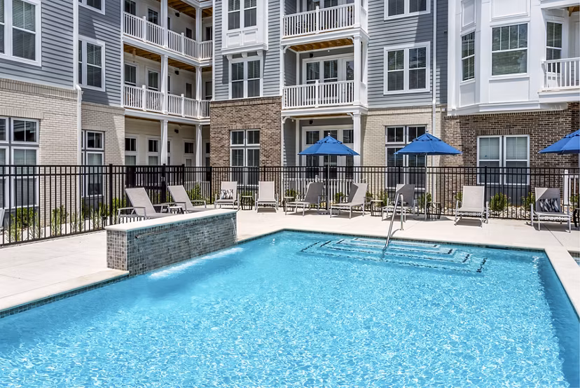 Outdoor pool with surrounding lounge chairs at Everleigh Short Pump Apartments, ideal for relaxing and socializing in a luxury setting