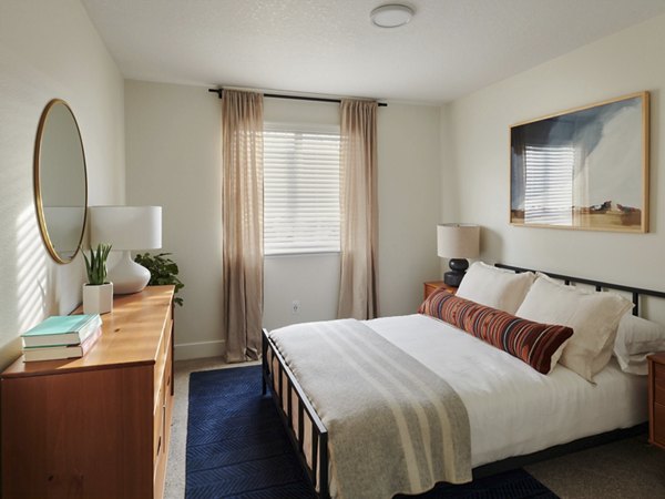 Bedroom featuring modern decor and large windows in Cedar House Apartments