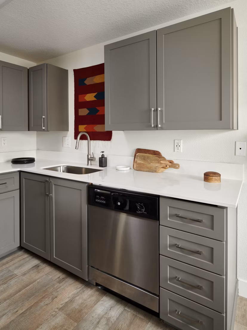 Modern kitchen with stainless steel appliances and granite countertops in Cedar House Apartments