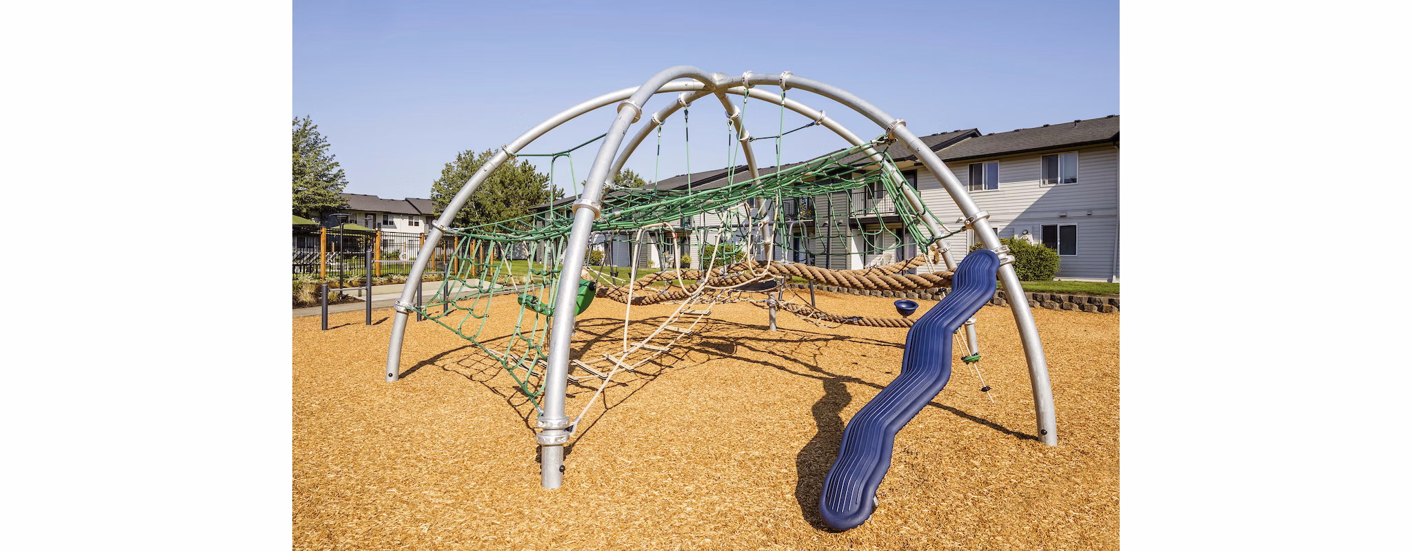 Modern playground with climbing structures and slides at Cedar House Apartments