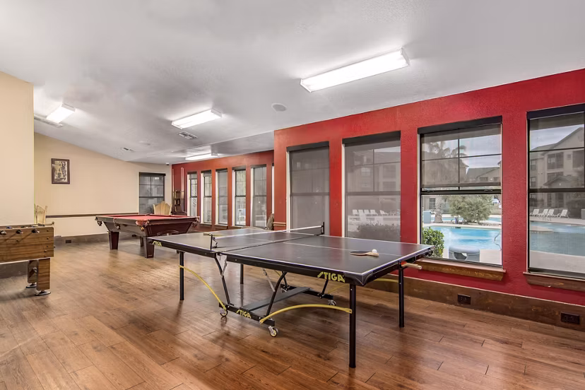 Game room with billiards and arcade games at Reveille Ranch Apartments, offering a fun leisure space for residents