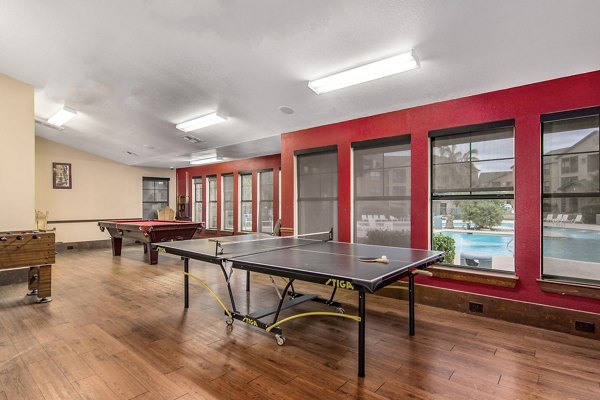Game room with billiards and arcade games at Reveille Ranch Apartments, offering a fun leisure space for residents