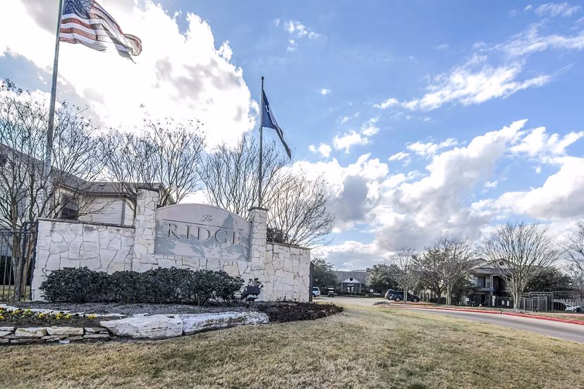 The Ridge sign with flags in front of luxury apartments surrounded by landscaped grounds