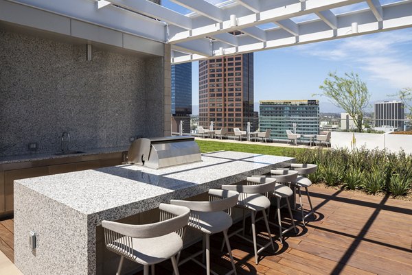 Grill area with modern outdoor seating at THEA at Metropolis Apartments, ideal for social gatherings and BBQs in an upscale urban setting
