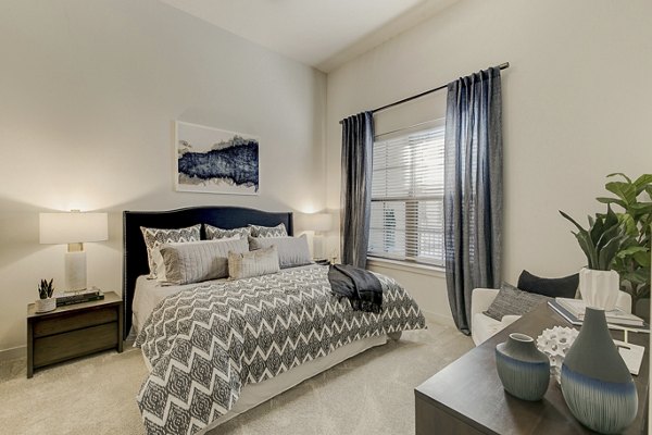 Cozy bedroom with modern decor at Addison Grove Apartments, featuring natural light and spacious layout