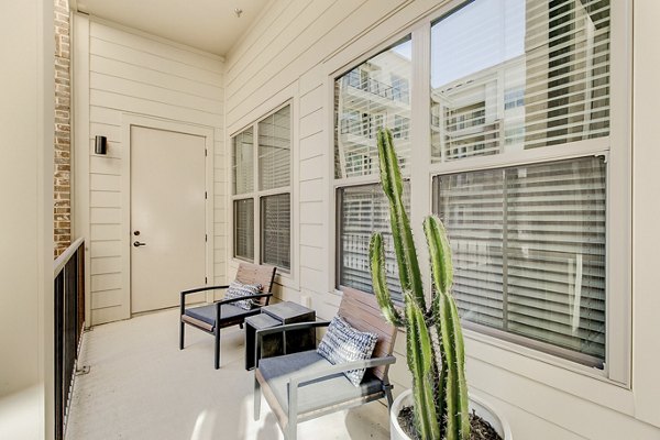 Outdoor patio area at Addison Grove Apartments featuring stylish seating under shaded pergola Ideal space for relaxation and socializing