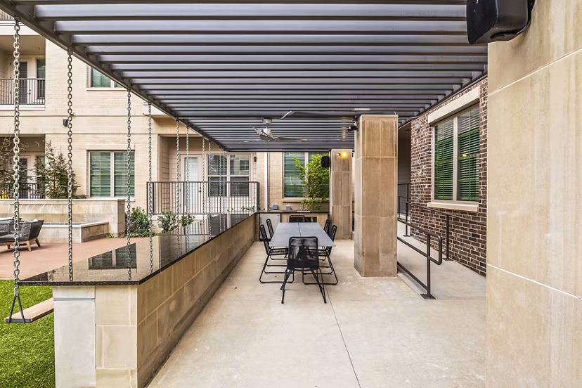 Outdoor BBQ grill area with seating at Elan Addison Grove Apartments