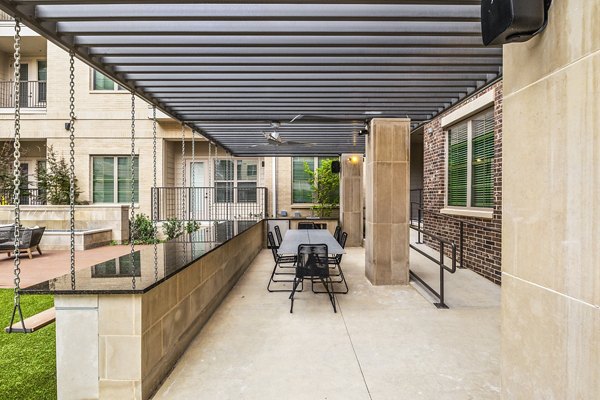 Outdoor BBQ grill area with seating at Elan Addison Grove Apartments