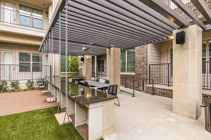 BBQ grill area at Elan Addison Grove Apartments: Modern outdoor space with seating and pergolas for social gatherings