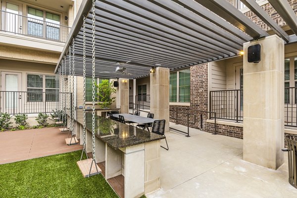 BBQ grill area at Elan Addison Grove Apartments: Modern outdoor space with seating and pergolas for social gatherings