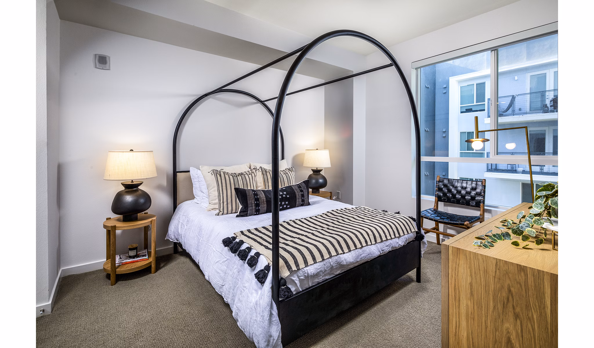 Spacious bedroom with modern decor at Be DTLA Apartments featuring city views