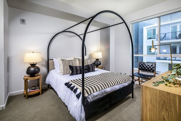 Spacious bedroom with modern decor at Be DTLA Apartments featuring city views