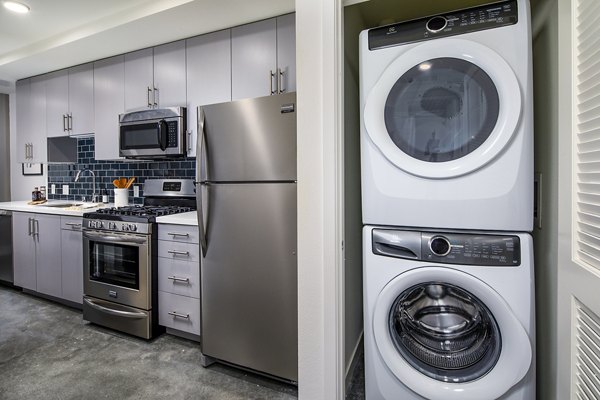 Modern kitchen featuring stainless steel appliances and granite countertops at Be DTLA Apartments