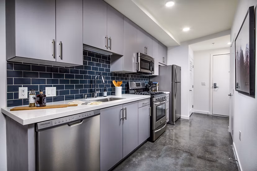 Modern kitchen with stainless steel appliances and quartz countertops at Be DTLA Apartments