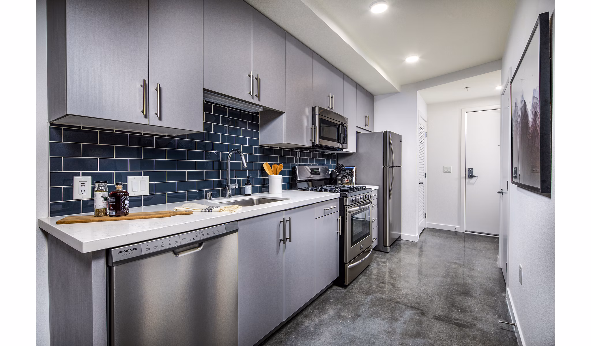 Modern kitchen with stainless steel appliances and quartz countertops at Be DTLA Apartments