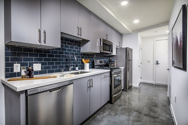 Modern kitchen with stainless steel appliances and quartz countertops at Be DTLA Apartments