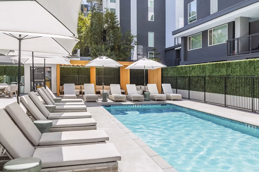 Resort-style pool with sleek sun loungers at Be DTLA Apartments, perfect for relaxation and leisure in Los Angeles luxury living