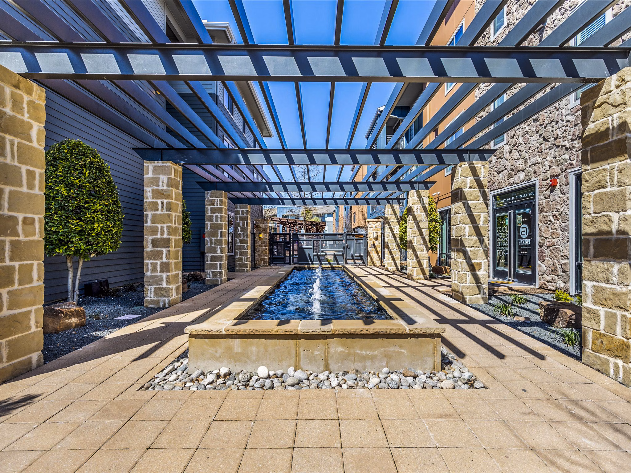 Patio with modern seating and lush landscaping at The Avery on Southwestern Apartments, offering luxury outdoor relaxation spaces