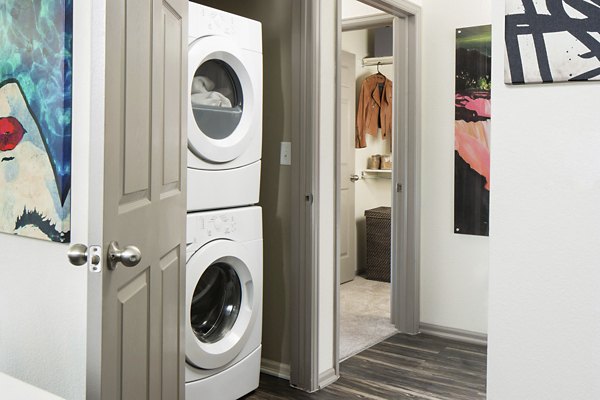 Laundry room with modern machines and ample storage at Griffis at Lowry Apartments, perfect for convenient and efficient laundry days