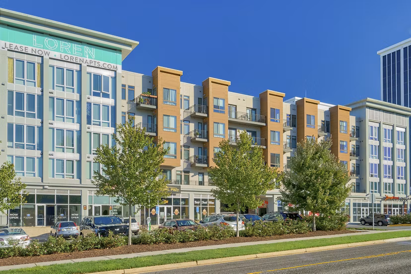 Loren: Modern luxury apartment building surrounded by trees and parked cars under a clear blue sky