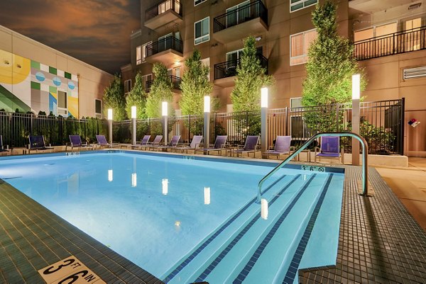 Outdoor swimming pool with lounge chairs and trees at luxury apartments