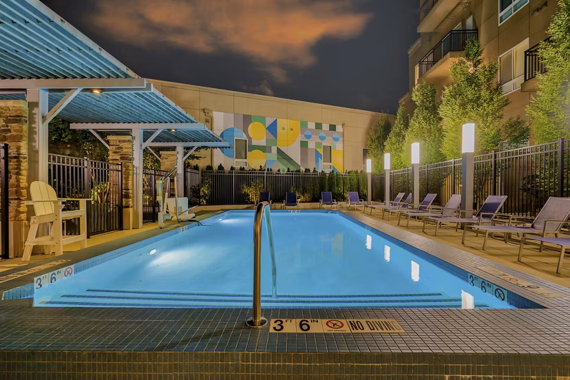 Stylish swimming pool area with lounge chairs and a vibrant mural at luxury apartments