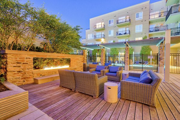 Stylish outdoor patio with wicker furniture and a fire feature at luxury apartments